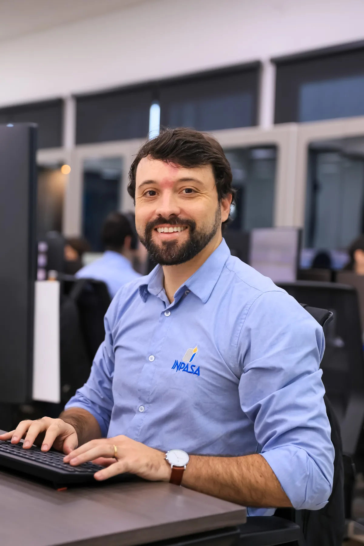 Funcionário da Inpasa sorrindo, sentado ao computador no escritório